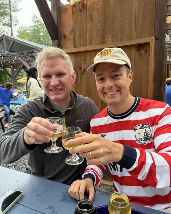Two guests toasting half pours outdoors at Allagash