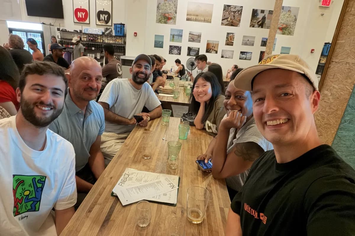 A long table of Rounds guests at Finback in Brooklyn, glasses and a tasting menu between them